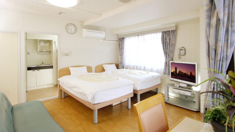 ベッドが2つ、ソファ、テレビがある203号室の写真